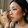 Young Asian woman with dewy skin showing completed ABG makeup look with sharp eyeliner and glossy lips