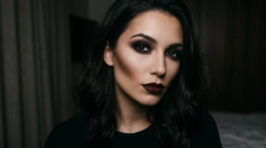 Woman with complete dark feminine makeup featuring smoky charcoal eyes and wine-toned lips