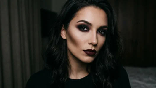 Woman with complete dark feminine makeup featuring smoky charcoal eyes and wine-toned lips
