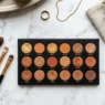Overhead view of bronze eyeshadow palette with multiple warm shades and various makeup brushes on marble surface
