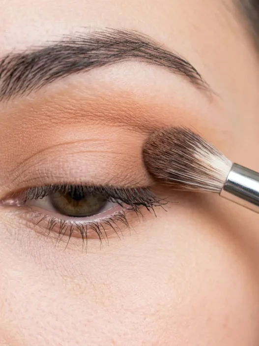 Fluffy makeup brush blending transition shade into eye crease with soft gradient forming