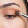 Fluffy makeup brush blending transition shade into eye crease with soft gradient forming