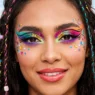 Woman wearing vibrant festival makeup with bold graphic colors and shimmer in editorial style