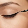 Liquid eyeliner brush creating precise winged tip at outer corner of closed eye with clean line
