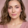 Woman wearing complete pink monochrome makeup look with matching pink styling and background in editorial portrait