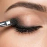 Close-up of smudger brush blending kohl pencil along lash line creating soft smokey gradient