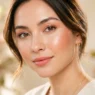 Woman with soft dewy spring makeup look featuring coral blush and glowing skin