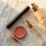 Summer makeup products including waterproof mascara and long-wear foundation arranged on marble surface