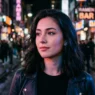 Woman with vampire-inspired makeup featuring neon street lighting reflecting on her face