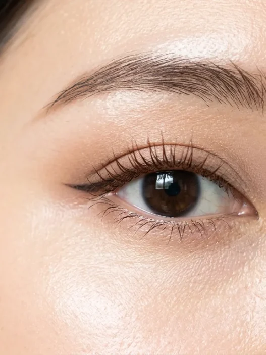 Close-up of eye area showing ABG makeup with dewy skin finish and brown mascara on natural lashes