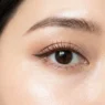 Close-up of eye area showing ABG makeup with dewy skin finish and brown mascara on natural lashes