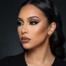 Model wearing complete baddie makeup look with sharp winged eyeliner and sculpted contour in three-quarter profile view