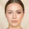 Woman showing completed natural makeup look with flawless base and subtle eye makeup