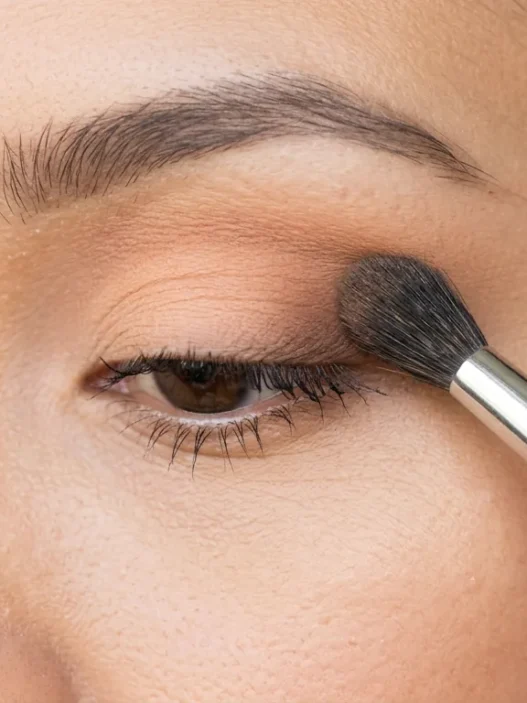 Fluffy makeup brush blending eyeshadow transition shade into eye crease with soft gradient effect