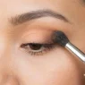 Fluffy makeup brush blending eyeshadow transition shade into eye crease with soft gradient effect