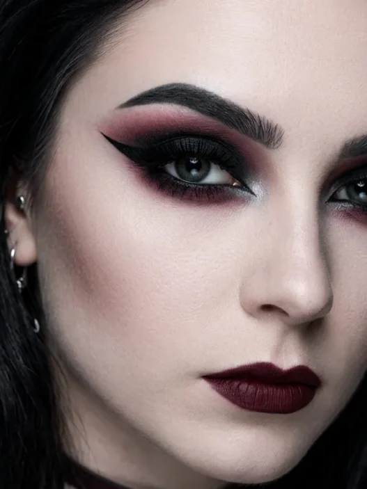 Complete gothic eye makeup look with smoky black eyeshadow, burgundy undertones, and sharp winged eyeliner on pale skin