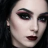 Complete gothic eye makeup look with smoky black eyeshadow, burgundy undertones, and sharp winged eyeliner on pale skin