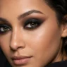 Close-up beauty portrait showing dramatic smoky eye makeup with deep blended shadows in dark moody lighting