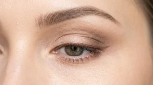 Close-up of one eye during makeup tutorial showing application technique in bright even lighting