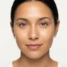 Close-up of a warm olive-toned face with a freshly primed luminous skin base in bright studio lighting