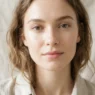 Woman with luminous barely-there makeup and loose natural hair against soft linen fabric in bright airy light