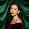 Woman with classic red lips and vintage waves against emerald velvet backdrop in side light