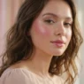 Woman with dewy rose blush and glossy pink lips under soft diffused light