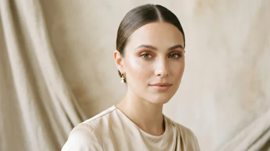 Woman with soft bronze eyeshadow and nude lips in champagne top under soft studio light