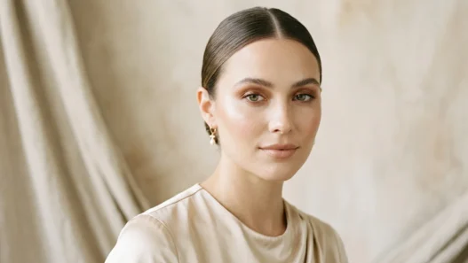 Woman with soft bronze eyeshadow and nude lips in champagne top under soft studio light