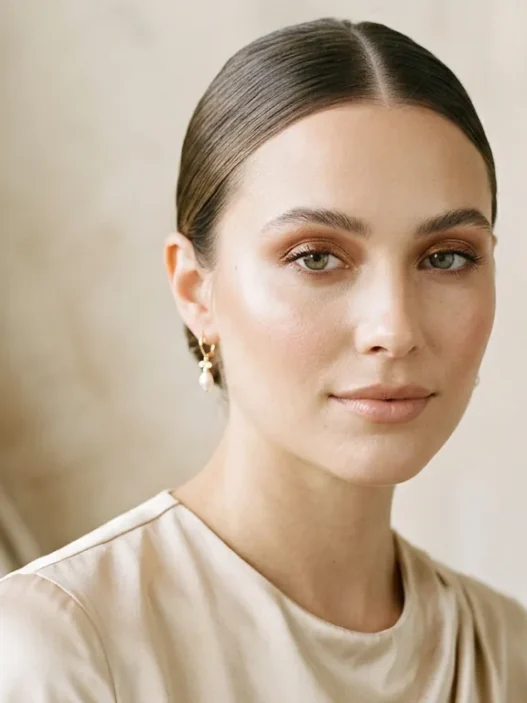 Woman with soft bronze eyeshadow and nude lips in champagne top under soft studio light