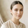 Woman with soft bronze eyeshadow and nude lips in champagne top under soft studio light