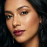 Woman with festive golden party makeup and glowing skin against dark background