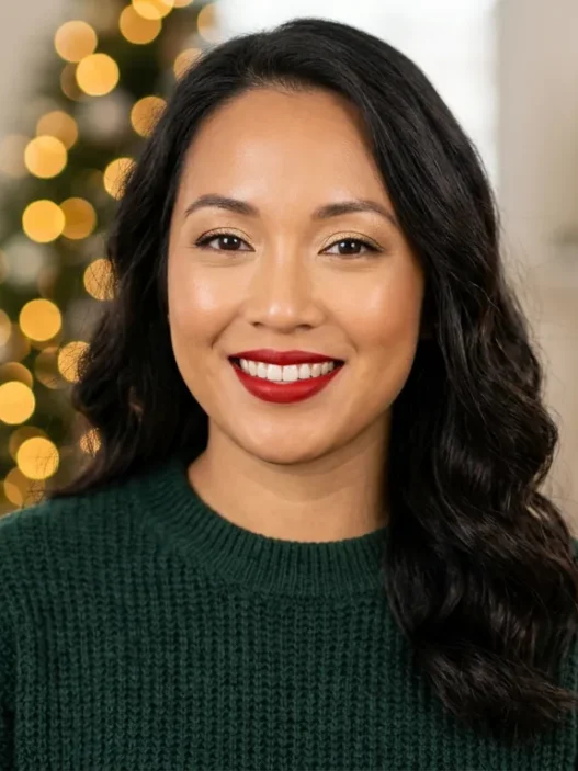 Woman wearing soft gold eyeshadow and red lipstick with glowing skin in holiday setting