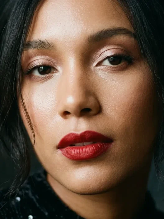 Woman with glowing holiday makeup and classic red lip in moody light