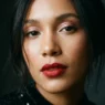 Woman with glowing holiday makeup and classic red lip in moody light