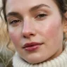 Woman with dewy winter clean girl makeup and berry balm lips in soft light